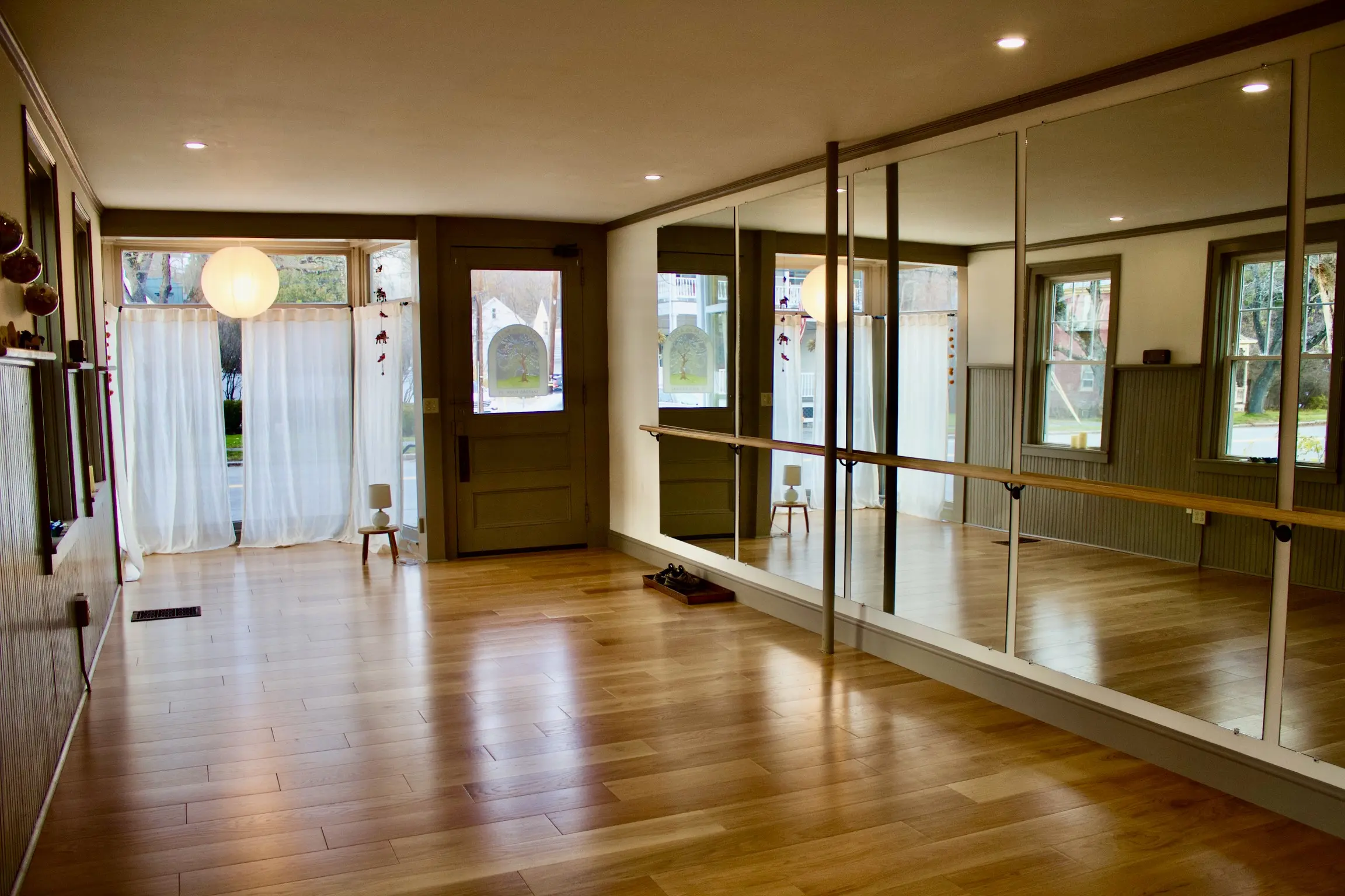 Spacious, well-lit room with wooden floors and mirrored wall panels.